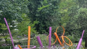 Un jardin agrémenté de parterres fleuris aux couleurs vives et de sculptures abstraites.