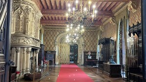 Un hall somptueux, avec un tapis rouge, un plafond en bois et un lustre.