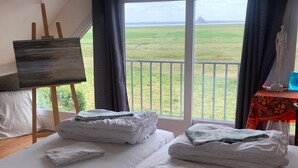 Camera da letto con un letto grande, un quadro su cavalletto e vista su un paesaggio verde dalla finestra.