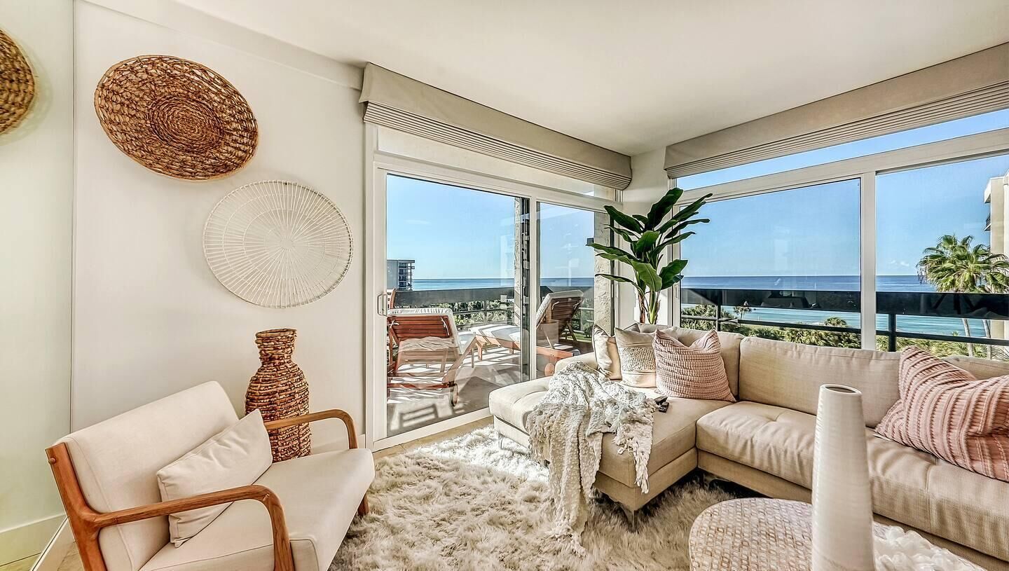 A modern living room with a large window, a sofa, a chair, and decorative items.