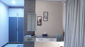 Moderni hotellihuone, jossa on pieni keittiö, vaatekaappi ja seinälle asennettu taideteos.