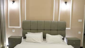 Habitació d'hotel amb un llit gran, dues taules de nit i il·luminació penjada a la paret.
