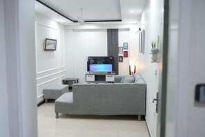 Una sala de estar moderna con un sofá gris, un televisor de pantalla plana y una mesita.