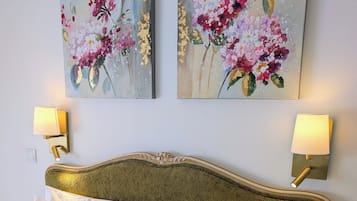 A neatly made bed with white linens and beige pillows, flanked by two wall-mounted lamps with white shades.