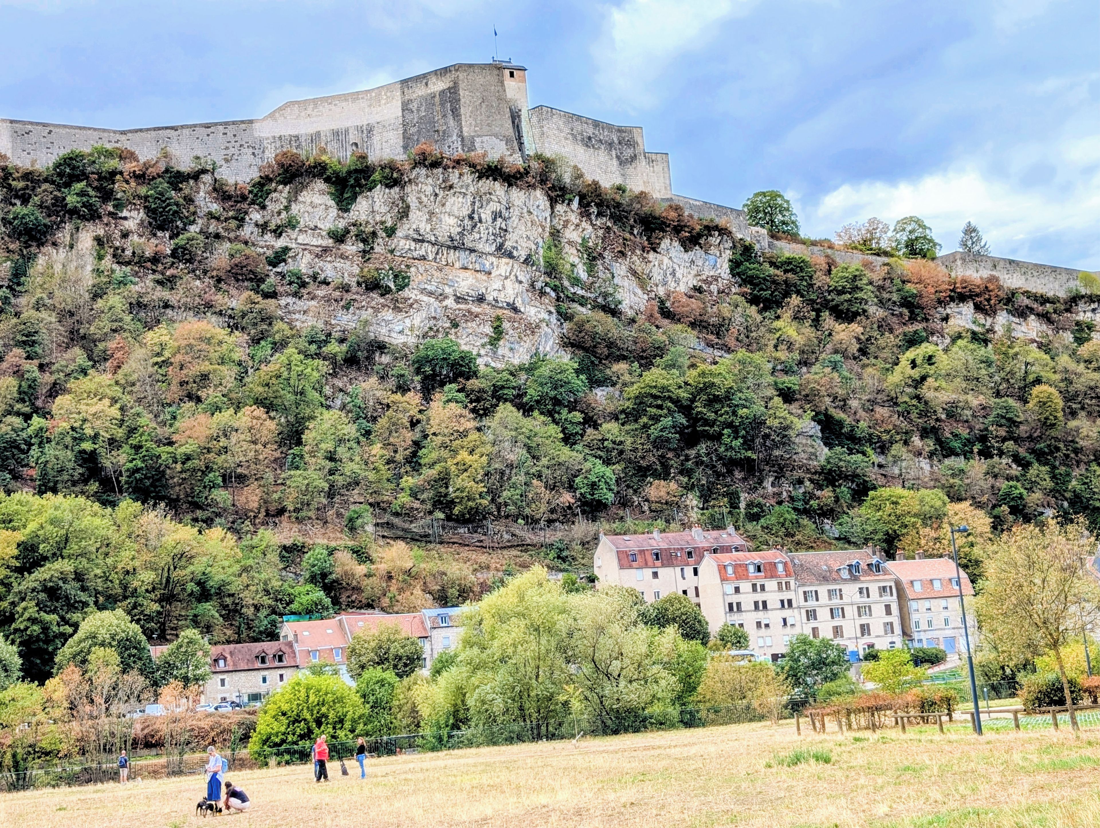 Une forteresse historique en pierre, située sur une colline, avec des bâtiments résidentiels à ses pieds.