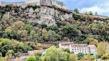 Une forteresse historique en pierre, située sur une colline, avec des bâtiments résidentiels à ses pieds.