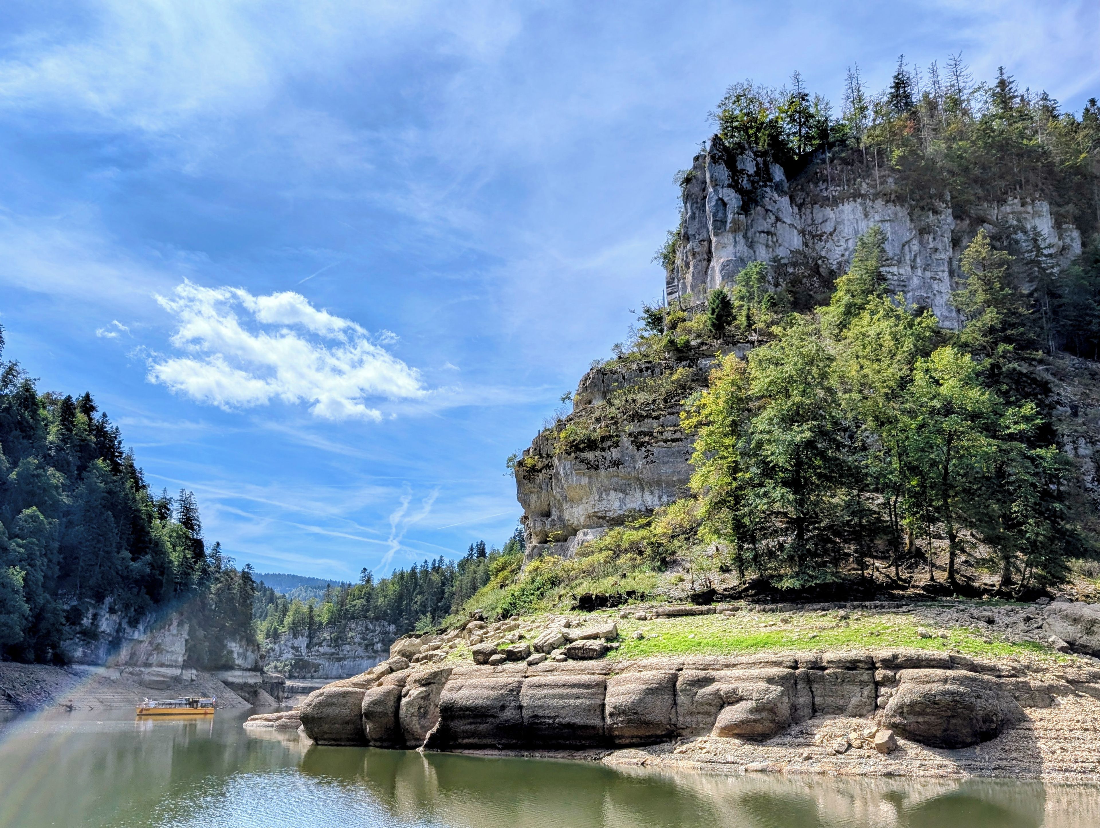 A natural landscape with a river, rocky cliffs, and dense forest.