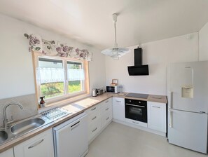 A modern kitchen with a sink, stove, microwave, and refrigerator.
