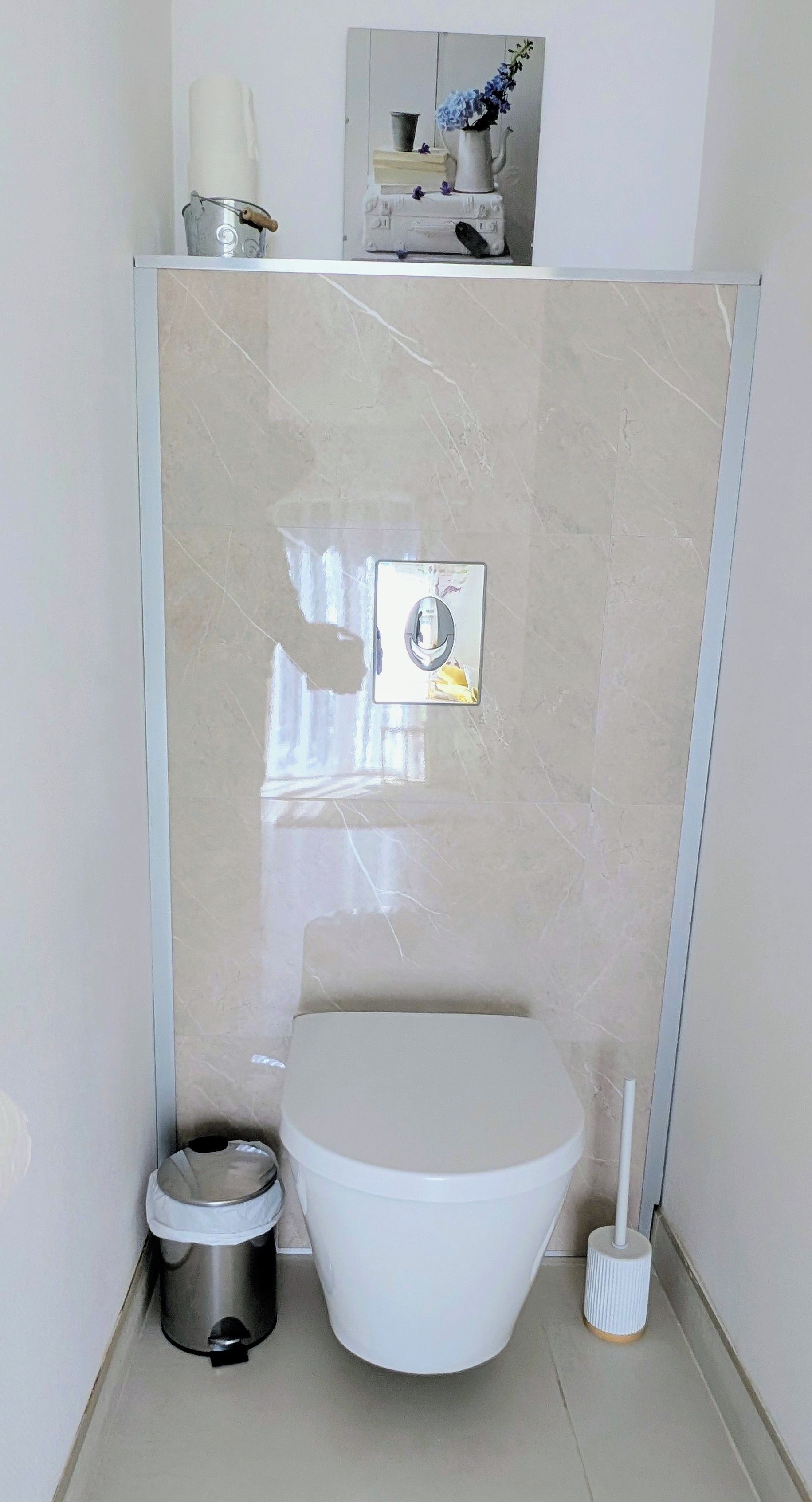Ein kleines Badezimmer mit Toilette, Mülleimer und Handtrockner.