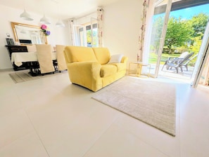 Un salon lumineux avec un canapé jaune, une table à manger et une grande fenêtre.