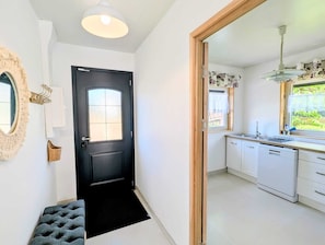 A hallway leading to a kitchen with a black door, a white wall, a mirror, and a basket. - 4-Star Comfort Villa with Air Conditioning in a Quiet Location & Beautiful Terrace; Parking 10 Minutes from Besançon (Dannemarie-sur-Crète)