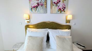 A hotel room with a bed, two wall-mounted lamps, and two floral paintings.