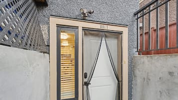 A hotel entrance with a beige door, a security camera above, and a barred gate to the right.