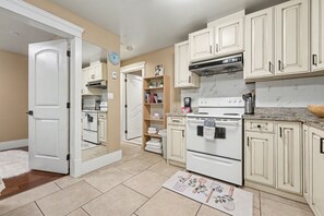 A kitchen with white cabinets, a stove, and a microwave. - Comfy 1 Bedroom Suite by Mroke Vacations (Vancouver)