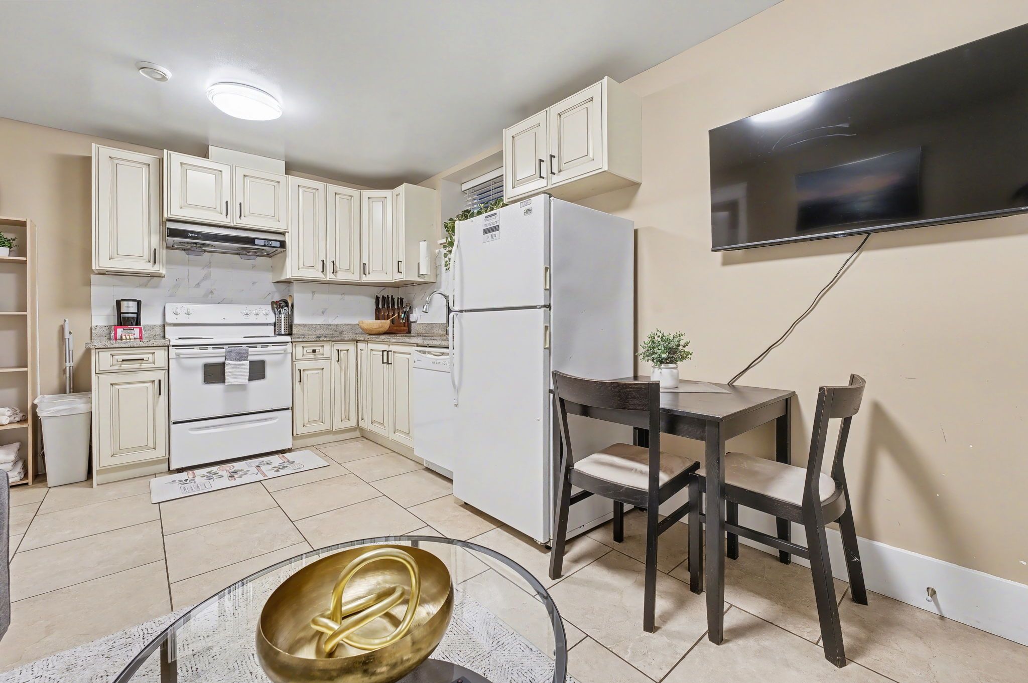 A kitchen with white cabinets, a refrigerator, a stove, and a dining table with chairs.