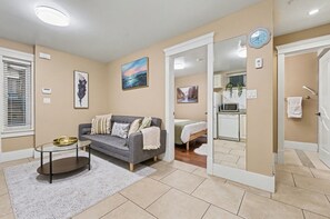 A living room with a sofa, coffee table, and artwork on the walls. - Comfy 1 Bedroom Suite by Mroke Vacations (Vancouver)