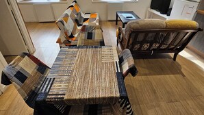 Une pièce avec un grand tapis tissé, deux canapés, une petite table, un téléviseur et un réfrigérateur.