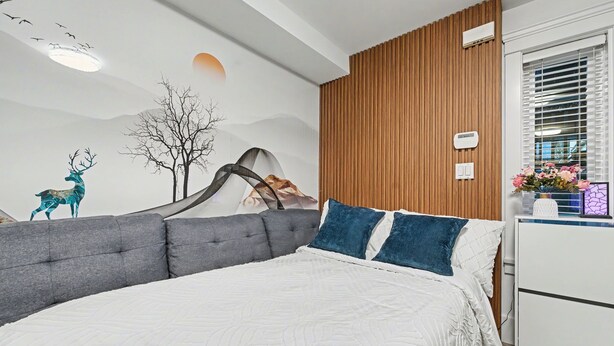 A modern bedroom with a large bed, a wooden panel wall, and a mural of a deer and mountains. - Quiant 2 Bedroom Suite by Mroke Vacations (Vancouver)