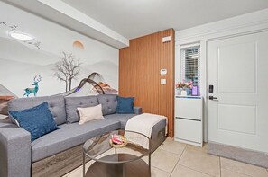 Una sala de estar moderna con un sofá gris, una mesa de centro de vidrio y una pared de acento de madera.