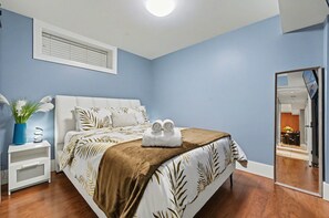 Un dormitorio con cama, mesita de noche, espejo y ventana con persianas.