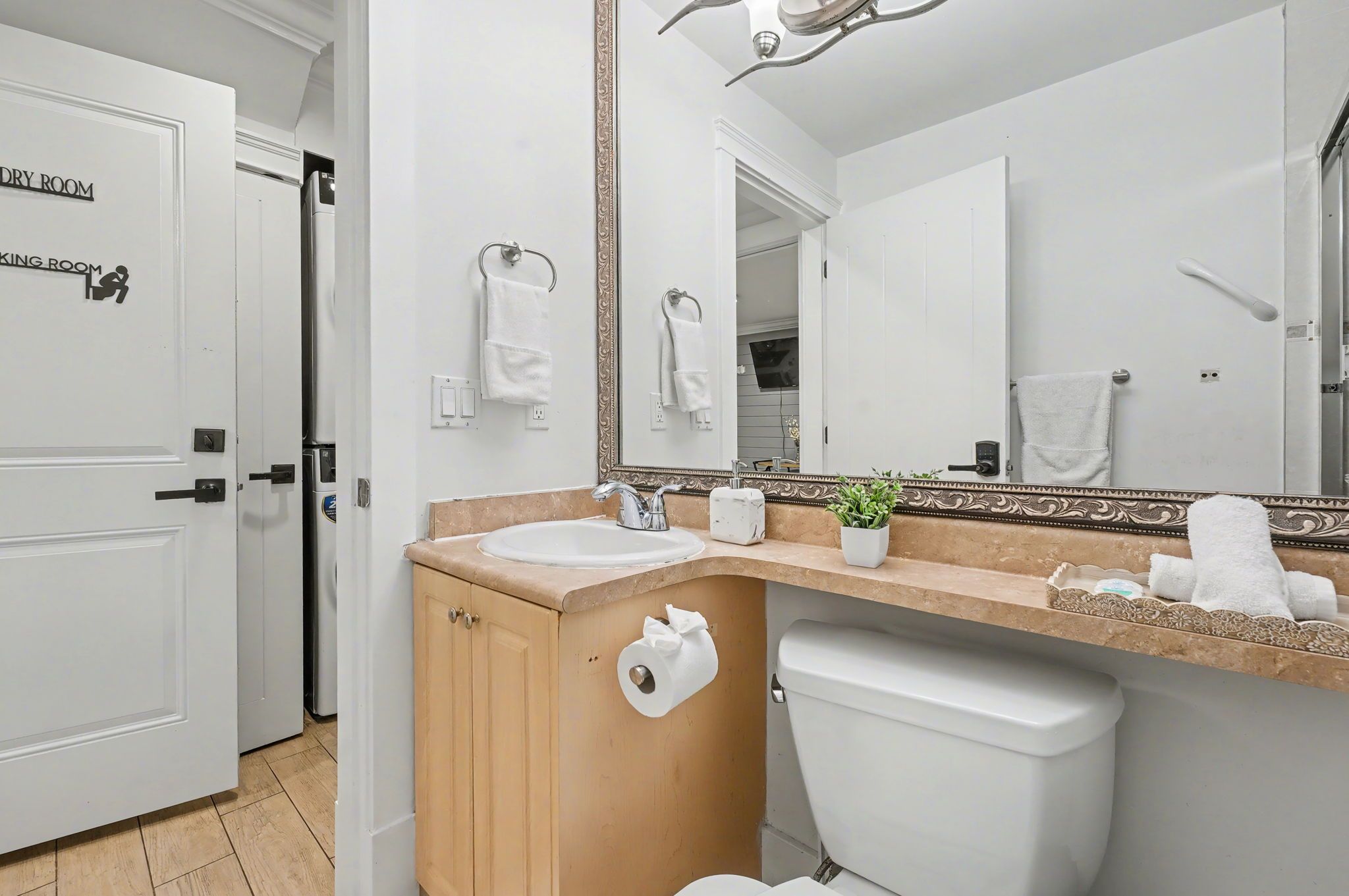 A bathroom with a sink, mirror, toilet, and a door labeled 'DRY ROOM.'
