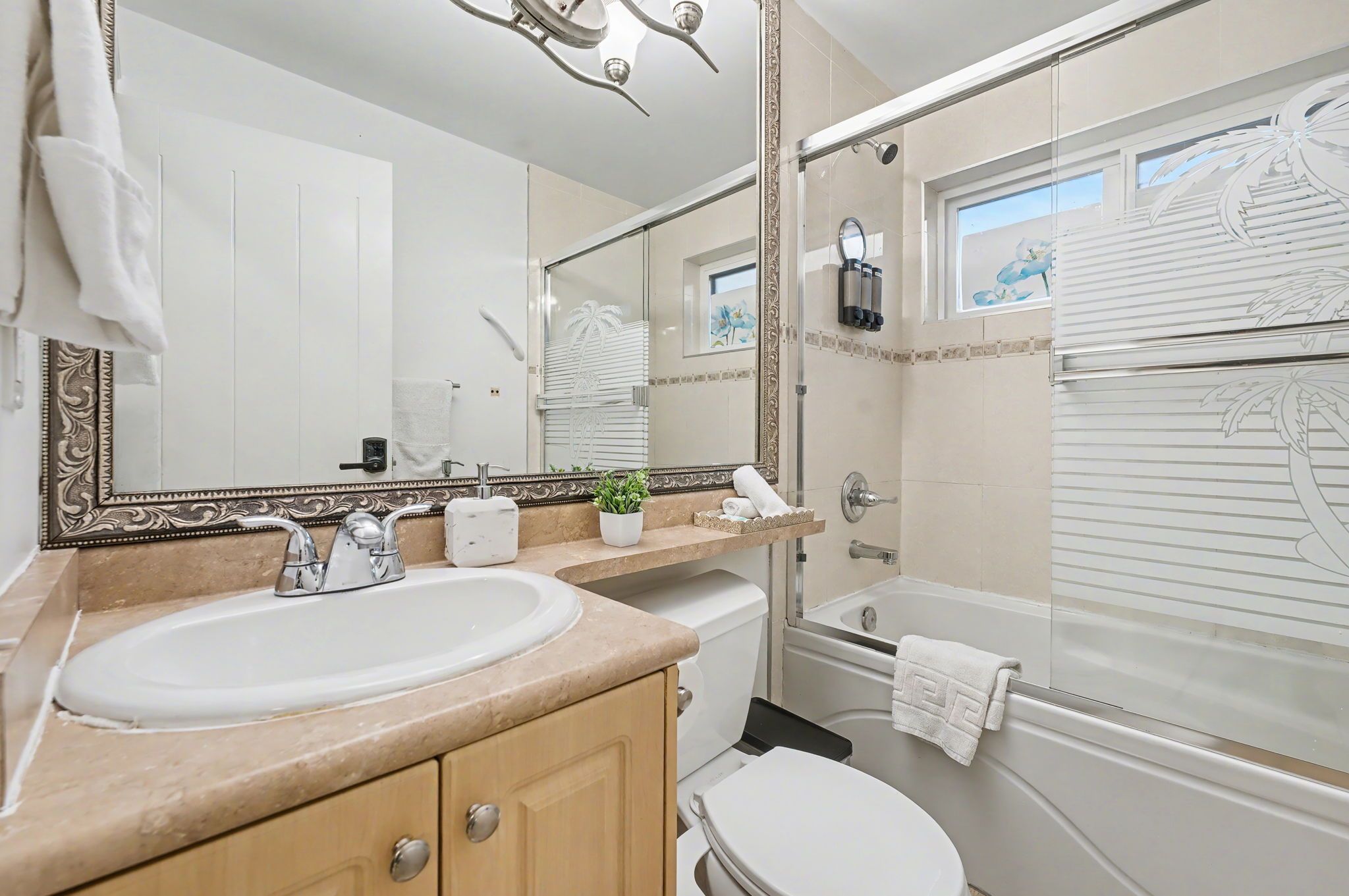 A bathroom with a large mirror, a sink, a toilet, and a shower area.