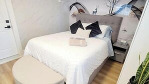 Un dormitorio con cama, mesita de noche y una planta en maceta.