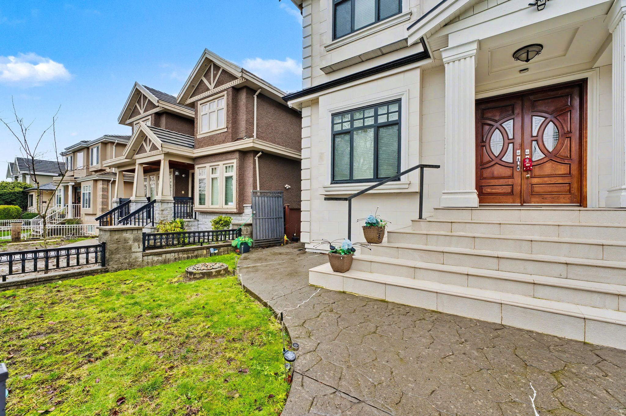 A residential street with houses featuring front porches, a stone pathway, and a well-maintained lawn.
