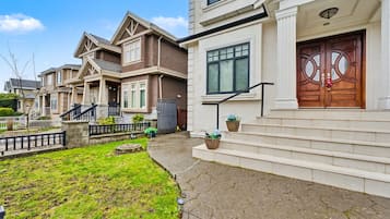 A residential street with houses featuring front porches, a stone pathway, and a well-maintained lawn.