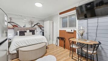 A modern bedroom with a bed, bedside table, and a small dining area with a table and chairs.