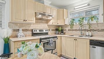 A modern kitchen with light wood cabinets, a stainless steel stove, and a dishwasher.