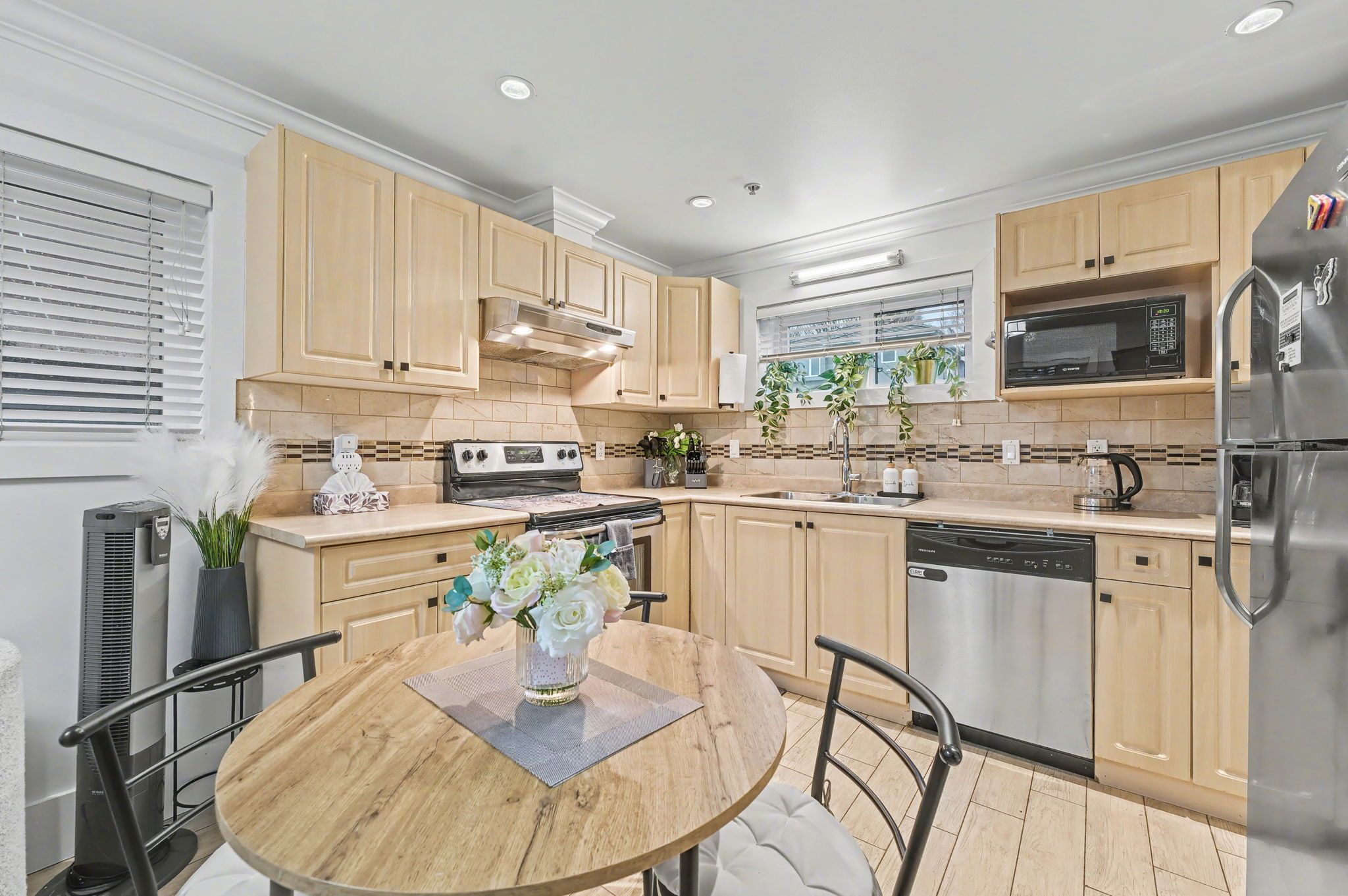 A modern kitchen with wooden cabinets, a stainless steel refrigerator, a microwave, and a dishwasher.