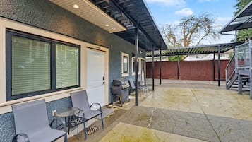 Un patio coperto con posti a sedere all'aperto, un barbecue e un portone garage con la scritta 'LANNYWAY'.