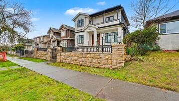 A row of townhouses with stone walls, a paved walkway, and a clear blue sky.