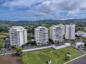 A modern apartment complex with multiple high-rise buildings, a parking area, and a grassy courtyard. - 7 Bedroom Penthouse Ocean & Mountain Views JB41001 (Jaco)