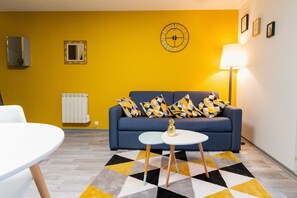 Ein Wohnzimmer mit einem blauen Sofa, einem weißen Tisch und einem Teppich mit Muster.