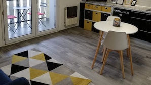 Una cuina moderna amb televisió, una zona de menjador amb taula i cadires, i una catifa amb dibuixos.