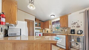 Una cocina con armarios de madera, una isla central, un microondas, una estufa y una zona de café.
