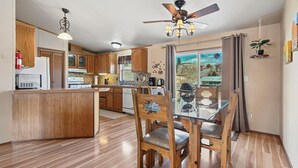 Una cocina con armarios de madera, una mesa de comedor de vidrio y un ventilador de techo.