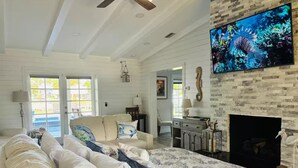 A spacious bedroom with a large bed, a TV mounted on a stone wall, and a fireplace. - Bring Boat! Heated Pool & Spa/Kayaks/Bikes/Fishing (Stuart)