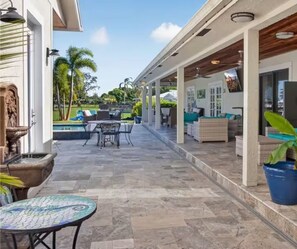 An outdoor patio area with a stone floor, a round table, and outdoor furniture. - Bring Boat! Heated Pool & Spa/Kayaks/Bikes/Fishing (Stuart)