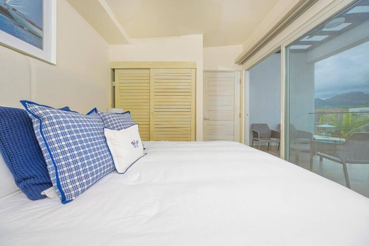 A bedroom with a large bed, a wooden closet, and a balcony with outdoor furniture.