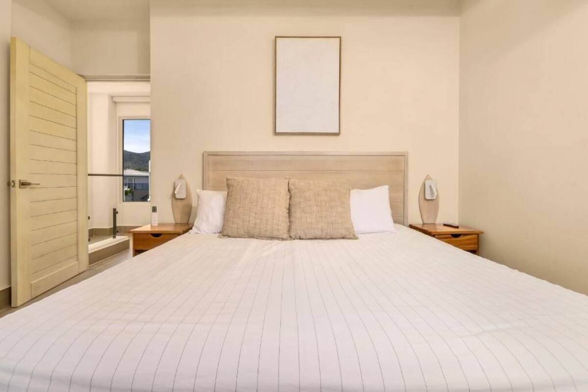 A bedroom with a large bed, two bedside tables, a headboard, and a framed picture on the wall.