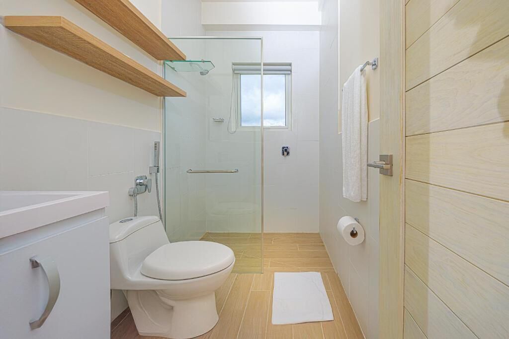 A modern bathroom with a toilet, shower, and glass-enclosed shower area.