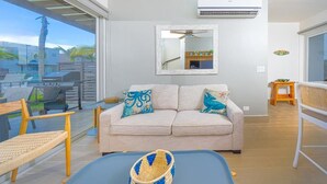 Ein modernes Wohnzimmer mit einer Couch, einem Deckenventilator und Blick ins Freie.