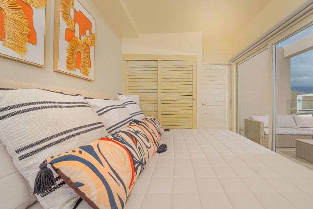 A bedroom with a bed, pillows, a window, and a sliding door leading to a balcony.