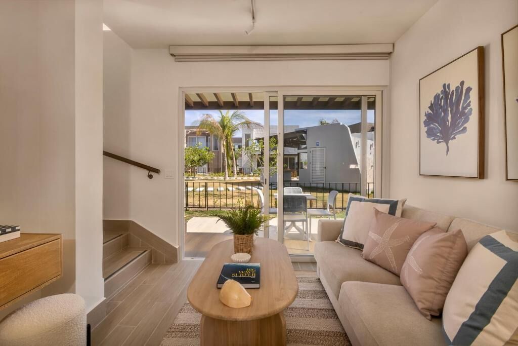 A modern living room with a sofa, a coffee table, and a staircase leading to a balcony.
