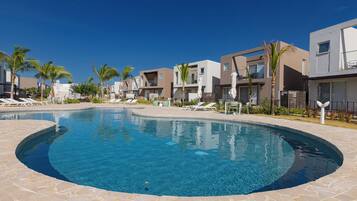 A modern resort with a swimming pool, lounge chairs, and contemporary buildings.