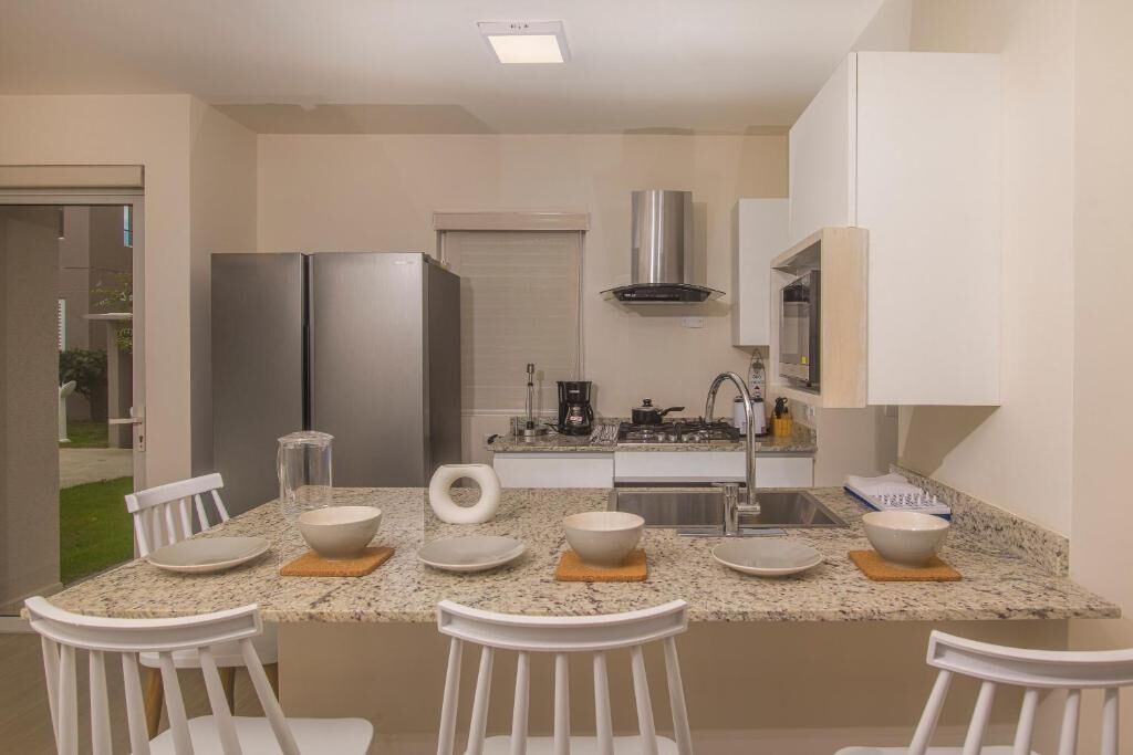Una cocina moderna con una isla central, armarios blancos y electrodomésticos de acero inoxidable.