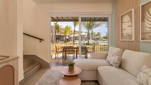 Ein Wohnzimmer mit einer Couch, einem Couchtisch und Blick auf einen Poolbereich mit Gartenmöbeln.